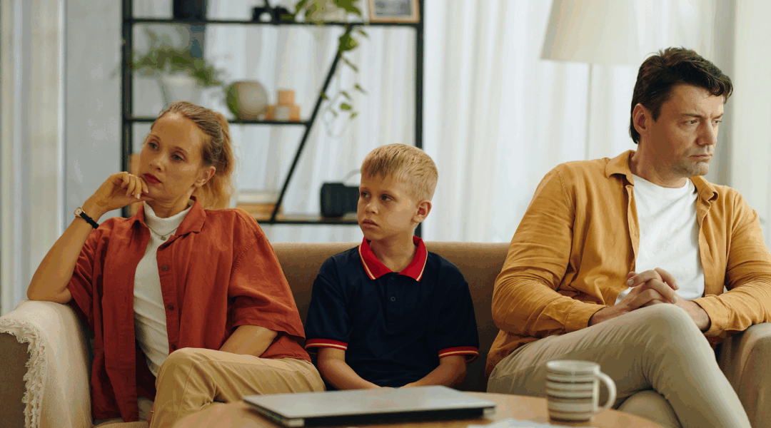 family on couch with kid in the middle parents not talking