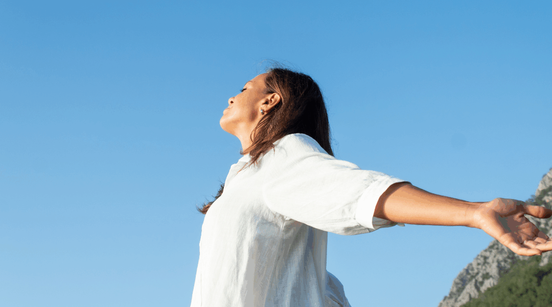 person looking at sun arms stretched out